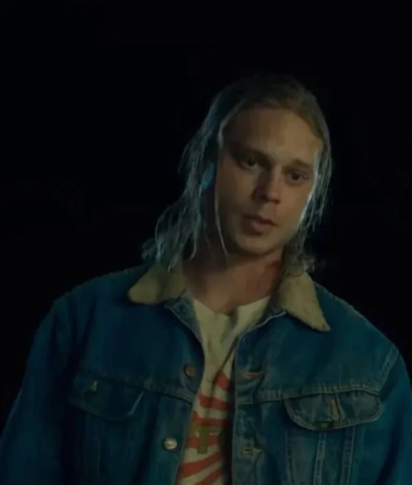 Josh Pafchek wearing a blue denim jacket in Honey Don’t!, featuring a button-up front, chest pockets, and classic faded wash design.